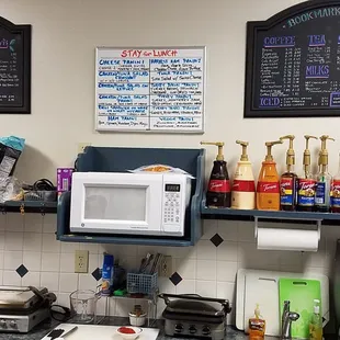 a kitchen counter with a microwave and a menu on the wall