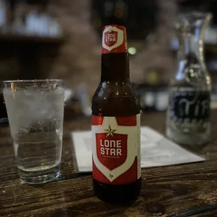 a bottle of lone star next to a glass of water