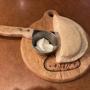 a piece of bread on a cutting board with a scoop of cream