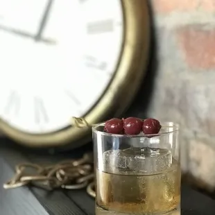 a glass of whiskey with cherries in it