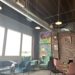 a room with chairs, tables, and paintings