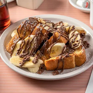 a plate of french toast with bananas and chocolate