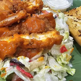a plate of chicken wings, salad, and bread