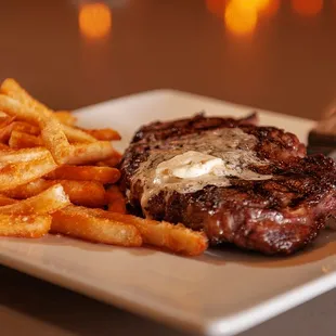 Steak with butter topping, fries, and steak knife at Brew Brothers.