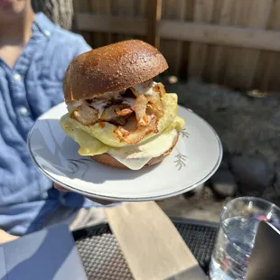 a person holding a plate with a sandwich on it