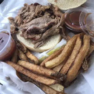 Pulled pork sandwich with fries and a deli pickle.