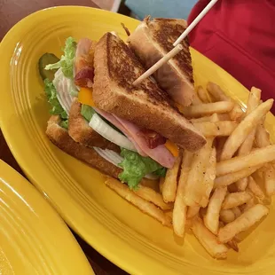 Club sandwich with a side and fresh French fries.