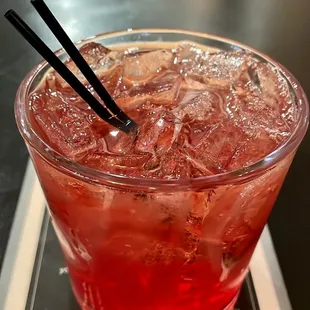 a red drink with ice and a pair of chopsticks