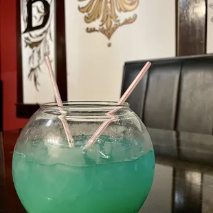 a glass of blue liquid with two straws in it