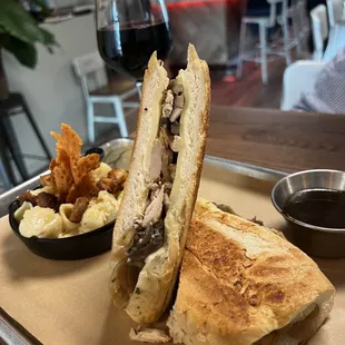 a sandwich with a side of chips and a glass of wine