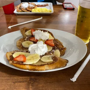 a plate of french toast with bananas and strawberries
