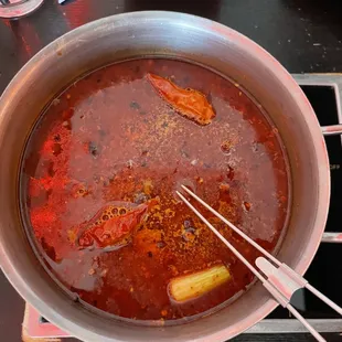 a pot of stew with tongs