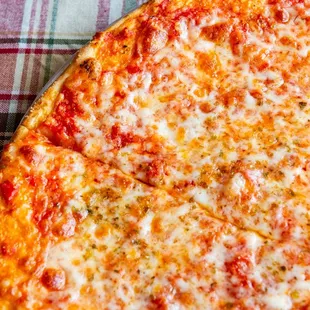 a cheesy pizza on a checkered tablecloth
