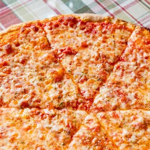 a cheesy pizza on a checkered tablecloth