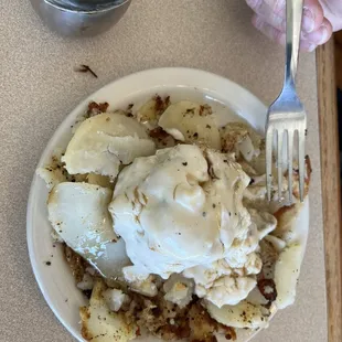 Half order biscuits and gravy on top of half order home fries.
