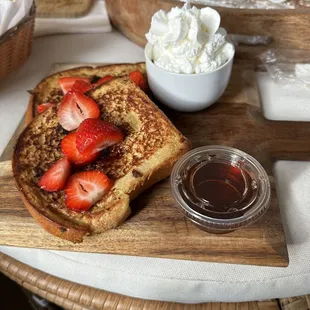 a plate of french toast with strawberries and whipped cream