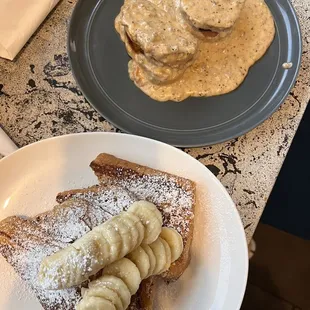 a plate of french toast with bananas and powdered sugar