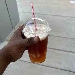 a hand holding a cup of iced coffee