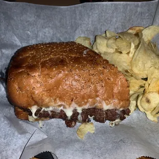 Steak and cheese with chips and a pickle