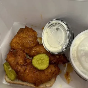 a fried chicken sandwich with pickles and sauce