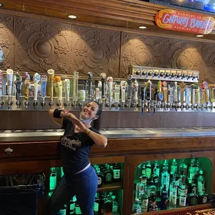 Michelle posing behind the bar showcasing the vast number of taps.