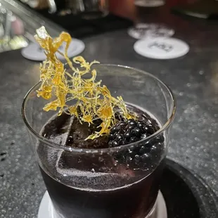 a cocktail with a garnish of blackberries