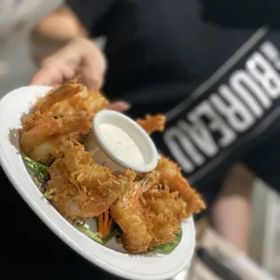 a person holding a plate of fried shrimp