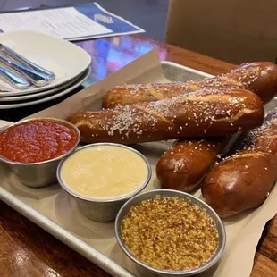 a tray of pretzels and dipping sauces