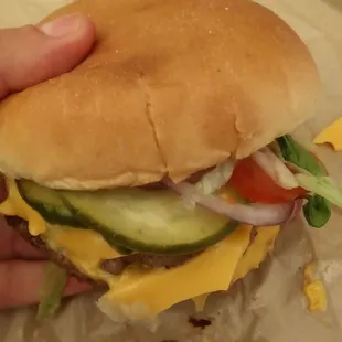 a hand holding a cheeseburger