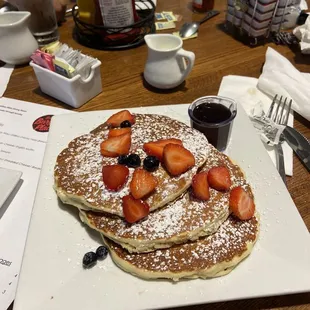 a stack of pancakes with strawberries and blueberries