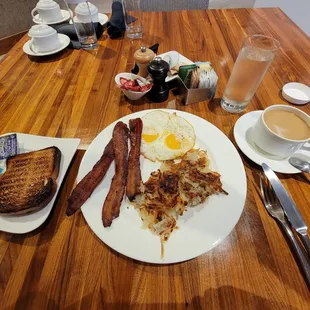 a breakfast of eggs, bacon, toast, and coffee