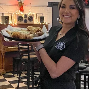 a waitress holding a tray of pastries
