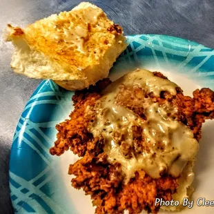 a plate of fried chicken with gravy and a biscuit