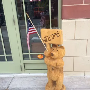 a bear holding a welcome sign