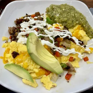 Three eggs sour cream sauce, bits of meat, cheese green salsa, avocado, diced tomatoes and peppers.