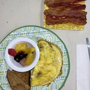 a breakfast plate with eggs, toast, fruit, and bacon