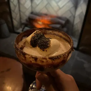a person holding a glass with a dessert in it