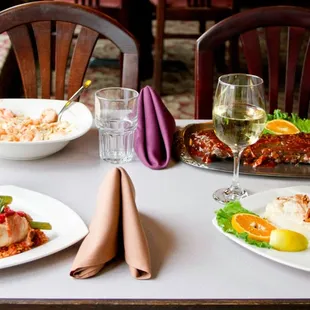 a table set with plates of food and glasses of wine