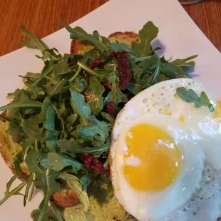 Krave Avocado Toast So fresh and healthy! arugula,sundried tomatoes, and 2 over meidium eggs on top