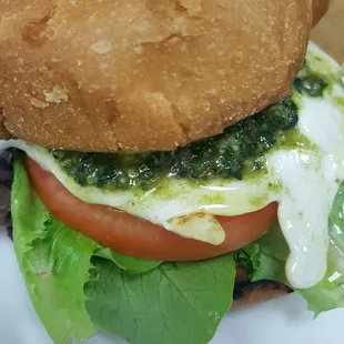 Krave breakfast basil sandwich homemade basil pesto, over med egg, swiss cheese, tomato and lettuce on brioche bun