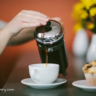 a person pouring coffee into a cup