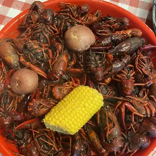 a bowl of cajuns, corn, potatoes, and corn on the cob