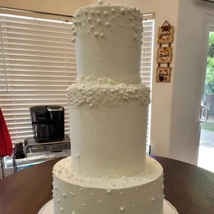 Three tier wedding cake, with the bottom tier being a faux cake.