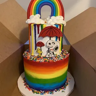 a rainbow colored cake with a rainbow umbrella