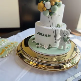 a white and green cake with balloons