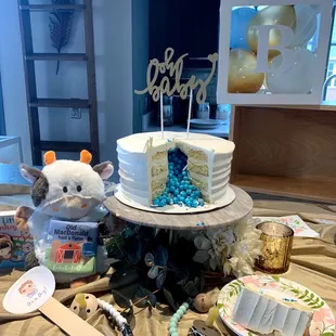 a table with a cake, cupcakes, and a teddy bear