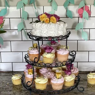 a three tiered cake and cupcakes