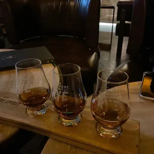 three glasses of whiskey on a wooden tray