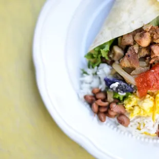 a burrito with beans, lettuce, and other toppings