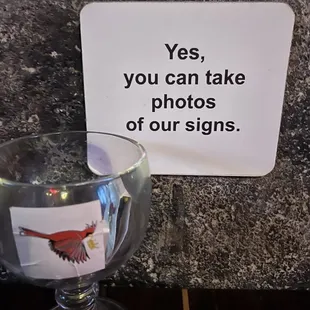 a glass of water and a sign that says yes, you can take photos of our signs